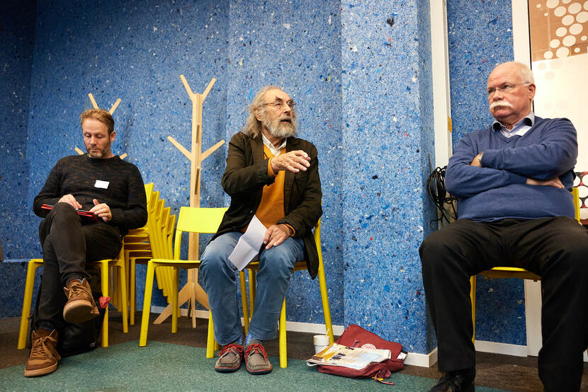 Drie deelnemers aan deelsessie zitten op stoelen, één van hen spreekt